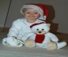 Boy with a Santa Claus hat with his teddy bear